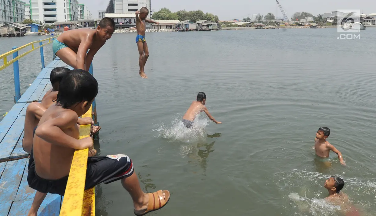 Sejumlah anak melompat saat bermain air dekat tanggul laut Muara Baru di Penjaringan, Jakarta Utara, Minggu (1/9/2019). Anak-anak memanfaatkan sisi tanggul laut raksasa (giant sea wall) sebagai   tempat  bermain alternatif. (merdeka.com/Arie Basuki)