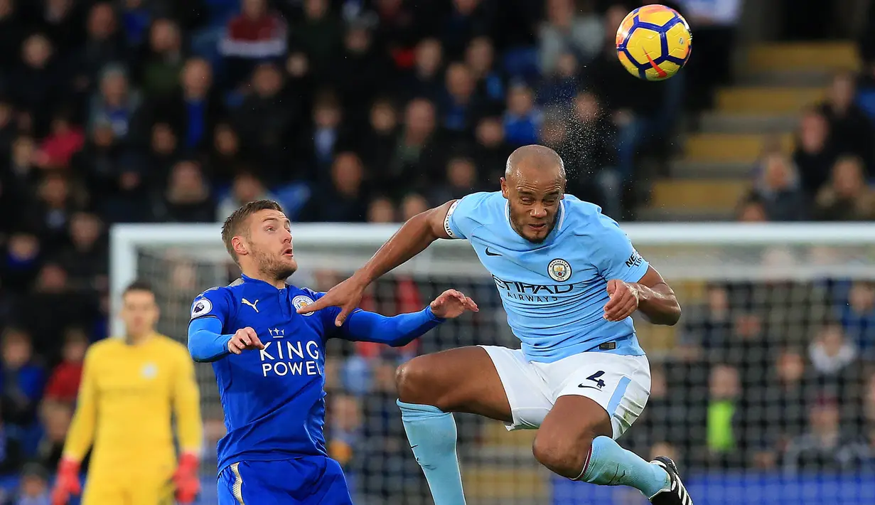 Bek Manchester City, Vincent Kompany, berebut bola dengan striker Leicester City, Jamie Vardy, pada laga Premier League di Stadion King Power, Sabtu (18/11/2017). Manchester City menang 2-0 atas Leicester City. (AFP/Lindsey Parnaby)