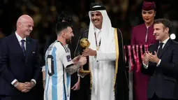 Emir Qatar Sheikh Tamim bin Hamad Al Thani menyerahkan penghargaan Bola Emas kepada Lionel Messi sementara Presiden Prancis Emmanuel Macron (kanan) bertepuk tangan pada akhir pertandingan sepak bola final Piala Dunia 2022 antara Argentina dan Prancis di Stadion Lusail, Lusail, Qatar, 18 Desember 2022. Lionel Messi dinobatkan sebagai peraih Bola Emas atau Golden Ball sebagai perlambang pemain terbaik selama Piala Dunia 2022 setelah memimpin Argentina menaklukkan Prancis dalam babak final. (AP Photo/Martin Meissner)