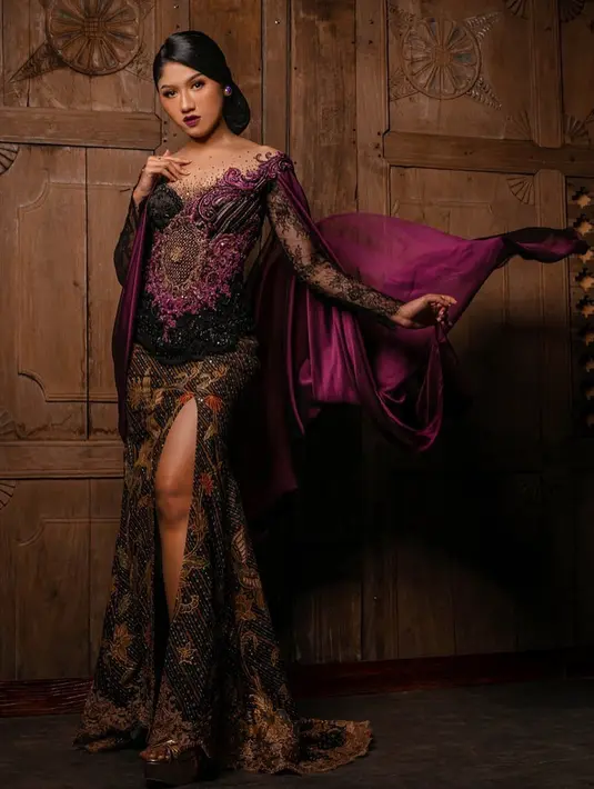 Masih dalam balutan kebaya yang dimodernisasi, kali ini Erina Gudono terlihat mengenakan rancangan Intan Avantie. Kebaya dengan aksen cape bernuansa ungu-hitam ini memiliki detail brokat yang cantik di bagian top-nya dan high slit untuk skirt-nya.