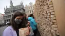 Seorang perempuan membaca kutipan pada balok kayu dari "The Disappearing Wall" di Grand Place, Brussel, Belgia, 3 Oktober 2020. Instalasi seni memperingati 30 tahun reunifikasi Jerman itu terdiri dari 6.000 balok kayu dilengkapi kutipan seniman dan pemikir dari seluruh dunia. (Xinhua/Zheng Huansong)