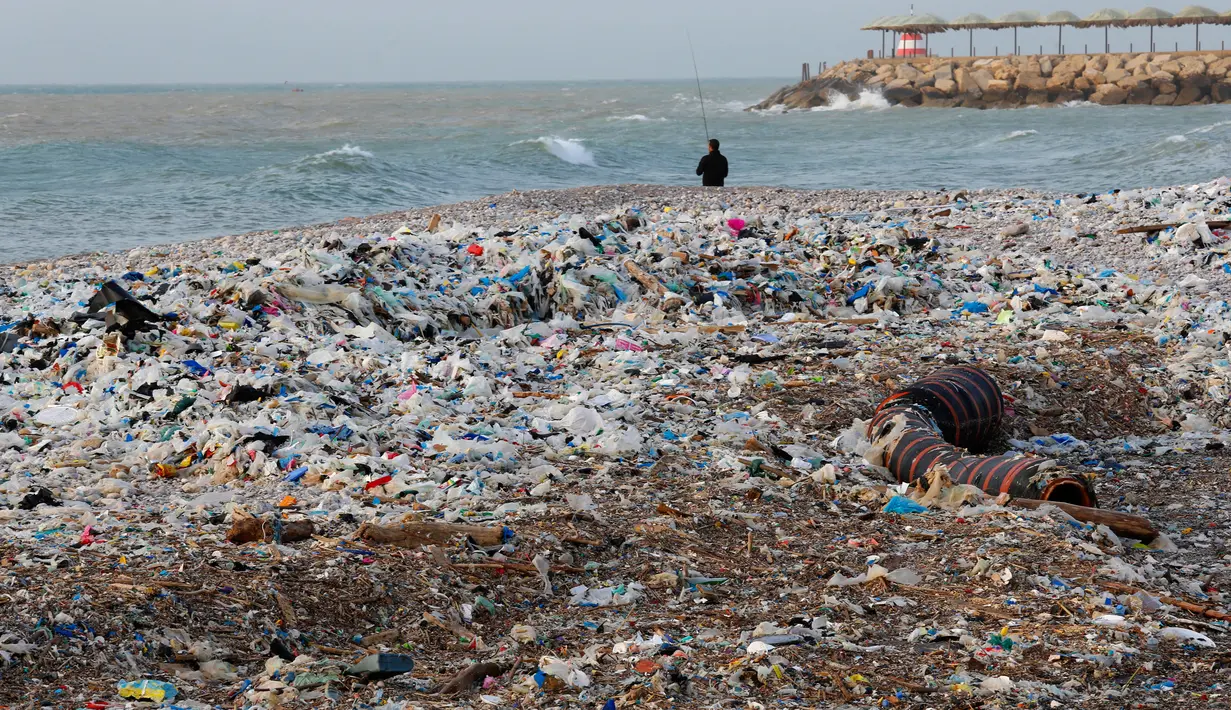 Seorang pria memancing dengan tumpukan sampah di belakangnya yang menutupi pantai Zouq Mosbeh di utara Beirut, Lebanon, 22 Januari 2018. Hampir segala limbah termasuk plastik hingga pembalut wanita menumpuk di pantai itu. (AP/Hussein Malla)