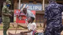 Aparat kepolisian menangkap pemuda yang masih berkeliaran di Kampala, Uganda (26/3/2020). Presiden Uganda Yoweri Museveni mengimbau masyarakatnya untuk tinggal di rumah selama 32 hari setelah 14 kasus positif Covid-19 teridentifikasi di negara tersebut. (AFP/Badru Katumba)