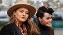 Dua pengunjung wanita, tampil cantik dengan topi di kepalanya jelang pembukaan ajang Pacuan Kuda dalam Festival Cheltenham di Inggris (16/3). Pacuan kuda merupakan olahraga yang disukai oleh kerajaan Inggris. (REUTERS/Paul Childs)