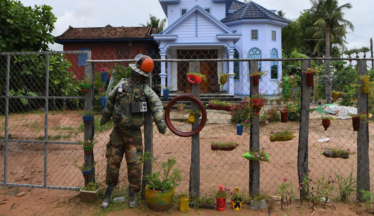 Orang-orangan sawah diikat ke pagar di depan sebuah rumah di provinsi Kampong Cham, Kamboja, 11 Oktober 2020. Para petani di desa itu menggunakan orang-orangan sawah atau disebut juga Tim Mong untuk menangkal virus corona  Covid-19 berdasarkan kepercayaan yang mereka yakini. (TANG CHHIN Sothy/AFP)