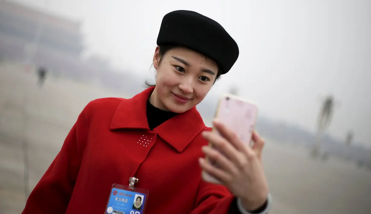 Seorang wanita selfie saat Kongres Rakyat Nasional China di Beijing, Sabtu (5/3/2016). Para wanita cantik ini hadir untuk menyambut para tamu delegasi NPC. (Reuters/Damir Sagolj)