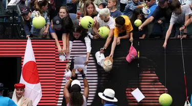 Petenis Jepang Naomi Osaka menandatangani benda yang disodorkan penonton usai mengalahkan petenis Republik Ceko Marie Bouzkova pada Australia Terbuka di Melbourne, Australia, Senin (20/1/2020). Penonton menyodorkan topi, bendera, hingga bola untuk ditandatangani Naomi. (AP Photo/Lee Jin-man)