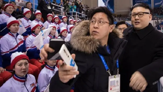 Kim Jong-un palsu dibawa pergi oleh petugas keamanan, sementara beberapa pemandu sorak berusaha untuk terus menyimak jalannya pertandingan hoki es. (Yelim Lee/AFP)