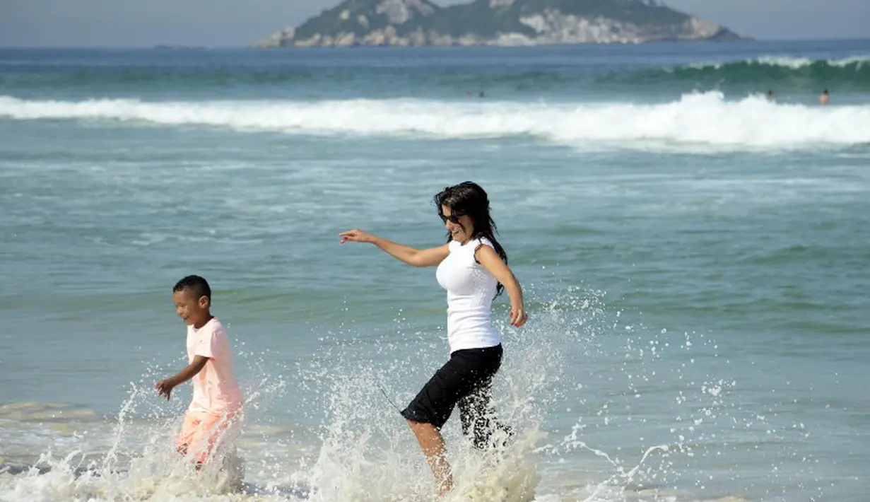  Ludivine tampak bercanda dengan anaknya di pantai Rio de Janeiro, Brasil (26/6/2014) (AFP PHOTO/FRANCK FIFE)