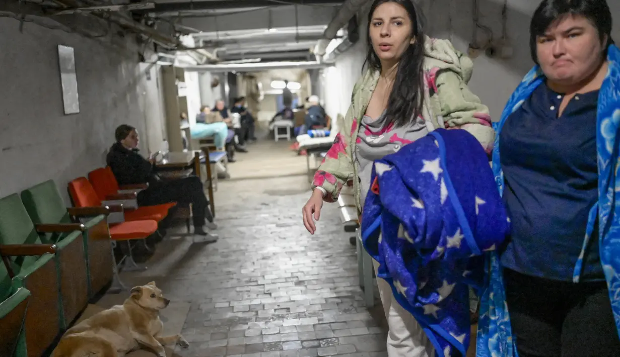 Seorang perempuan hamil berjalan dengan perawat di ruang bawah tanah rumah sakit bersalin saat peringatan sirene untuk serangan udara di Mykolaiv, Ukraina pada 14 Maret 2022. Mykolaiv, kota di tepi Laut Hitam dilaporkan menjadi target serangan pasukan Rusia selama berhari-hari. (BULENT KILIC/AFP)