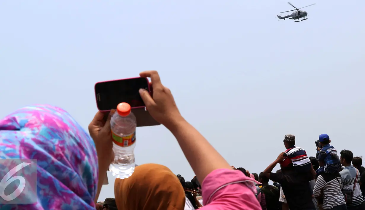 Warga mengabadikan helikopter saat gladi bersih HUT ke-70 TNI di Cilegon, Banten, Sabtu (3/10/2015). Jelang HUT ke-70 TNI tersebut menjadi daya tarik tersendiri bagi warga untuk menyaksikan secara dekat atraksi TNI. (Liputan6.com/Immanuel Antonius)