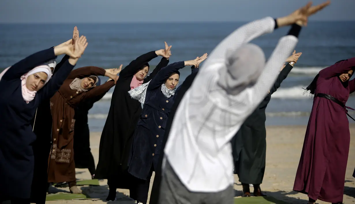 Sejumlah wanita Palestina berlatih yoga di pantai di Gaza City (3/3/2020). Pelatihan yoga tersebut diselenggarakan oleh Positive Energy Club. (AFP Photo/Mohammed Abed)