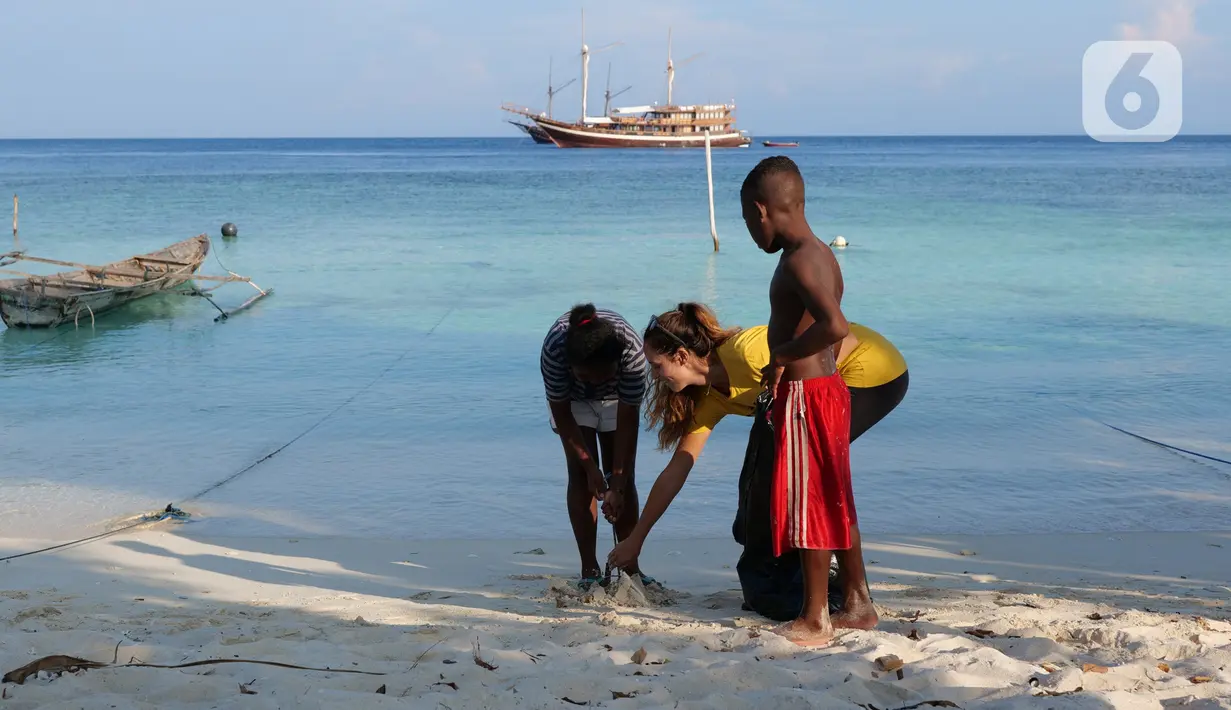 Aktivis AS, Carrie dan anak-anak membersihkan sampah plastik di bibir pantai Desa Sawandarek, Raja Ampat, Papua Barat (22/11/2019). Carrie mengajak anak-anak untuk membersihkan sampah setiap Jumat dengan berkunjung ke sejumlah desa atau pulau yang ada di Raja Ampat. (Liputan6.com/Herman Zakharia)