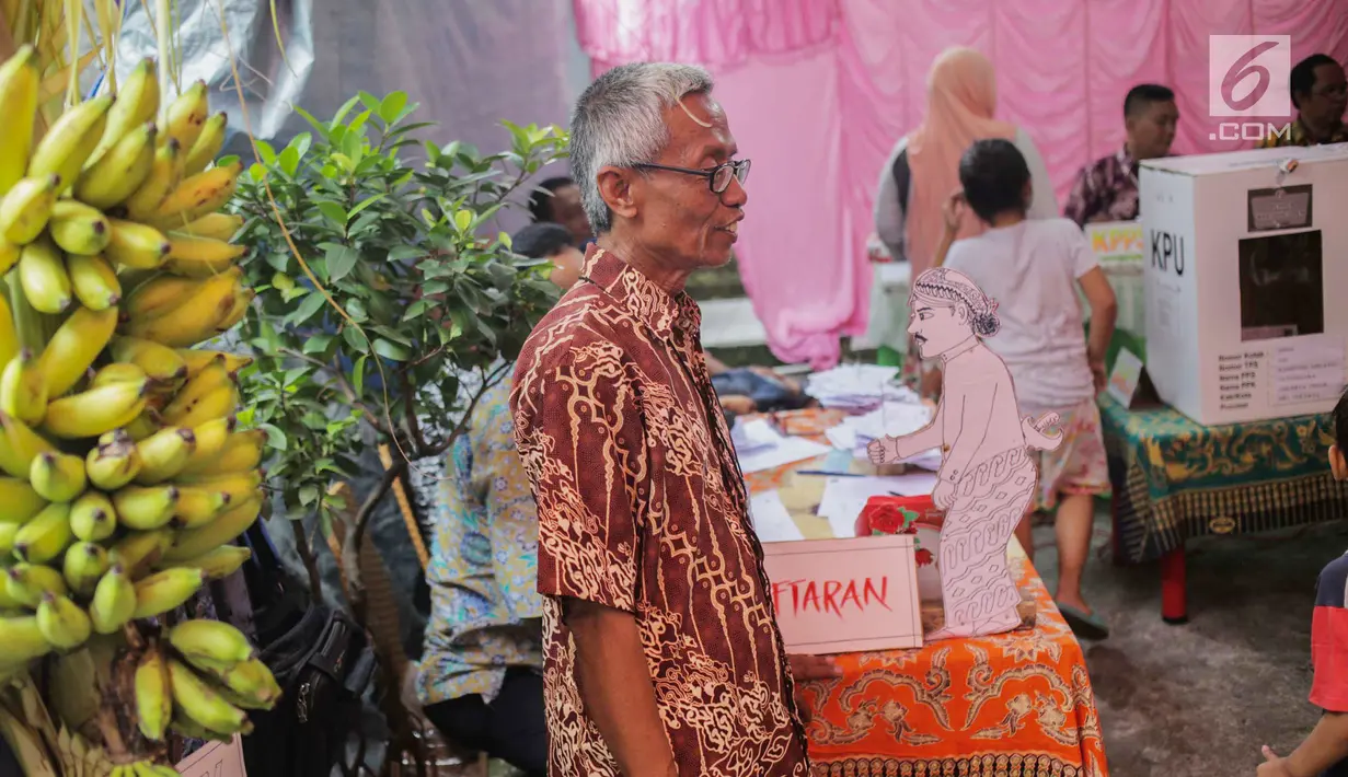 Petugas Kelompok Penyelenggara Pemungutan Suara (KPPS) mengenakan batik saat menyambut calon pemilih untuk mencoblos di TPS 45 Kebon Pala, Jakarta, Rabu (17/5). TPS tersebut mengambil tema suasana pernikahan adat Jawa untuk menarik minat pemilih dan menekan angka golput. (Liputan6.com/Faizal Fanani)