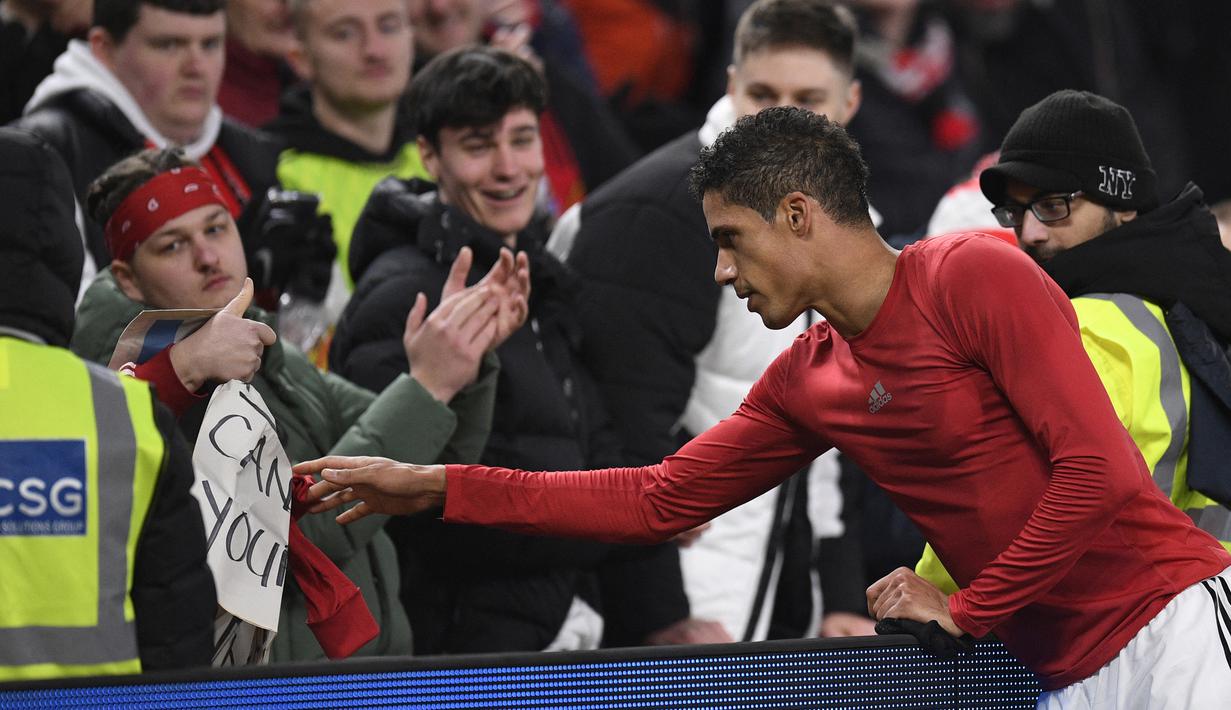 Bek Manchester United, Rapahael Varane memberikan jersey kepada seorang suporter usai laga Liga Inggris 2022/2023 menghadapi Leeds United di Old Trafford Stadium, Manchester (8/2/2023). Rapahael Varane yang kini memasuki musim kedua bersama Manchester United ini dilahirkan pada 25 April 1993 di Lille, Prancis. (AFP/Oli Scarff)