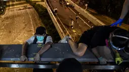 Demonstran menuruni jembatan menggunakan tali untuk melarikan diri dari Universitas Politeknik Hong Kong di Distrik Hung Hom, Hong Kong, Senin (18/11/2019). Lusinan demonstran melarikan diri dari Universitas Politeknik Hong Kong yang dikepung polisi selama berhari-hari. (Ye Aung Thu/AFP)