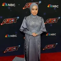 Di final AGT, Putri kembali mengenakan gaun rancangan Tiffany Liem. Kali ini, ia memilih gaun berwarna kebiruan yang memiliki ekor panjang hingga menyapu lantai. [@portalpageanti]