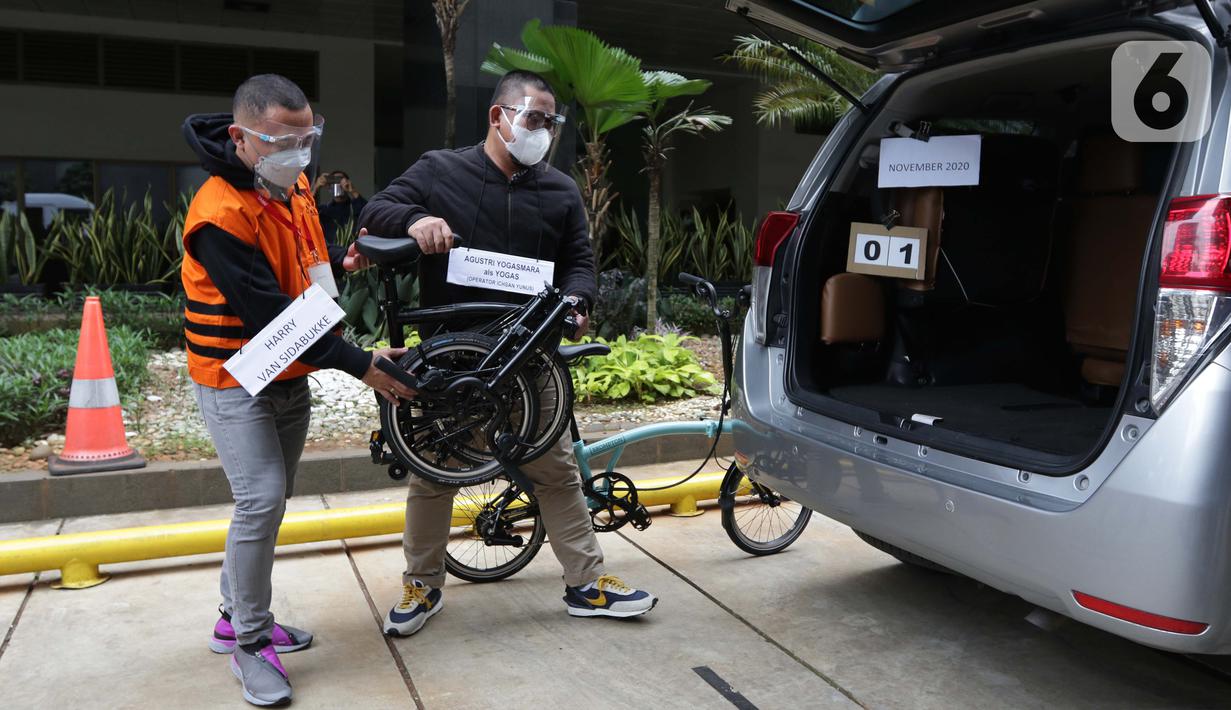Tersangka Harry Sidabuke (kiri) bersama perantara anggota Komisi II DPR Ihsan Yunus, Agustri Yogasmara mengangkat sepeda Brompton saat rekonstruksi perkara dugaan korupsi pengadaan bantuan sosial penanganan COVID-19 di gedung KPK, Jakarta, Rabu (10/2/2021). (Liputan6.com/Helmi Fithriansyah)
