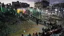 Lentera ini menjadi simbol ketahanan dan harapan di tengah gelapnya wilayah akibat krisis listrik. Tampa dalam foto, warga Palestina duduk di meja panjang di tengah reruntuhan bangunan yang hancur untuk berbuka puasa bersama, selama bulan suci Ramadan di Khan Younis, Jalur Gaza, Kamis 19 Februari 2026. (AP Photo/Abdel Kareem Hana)