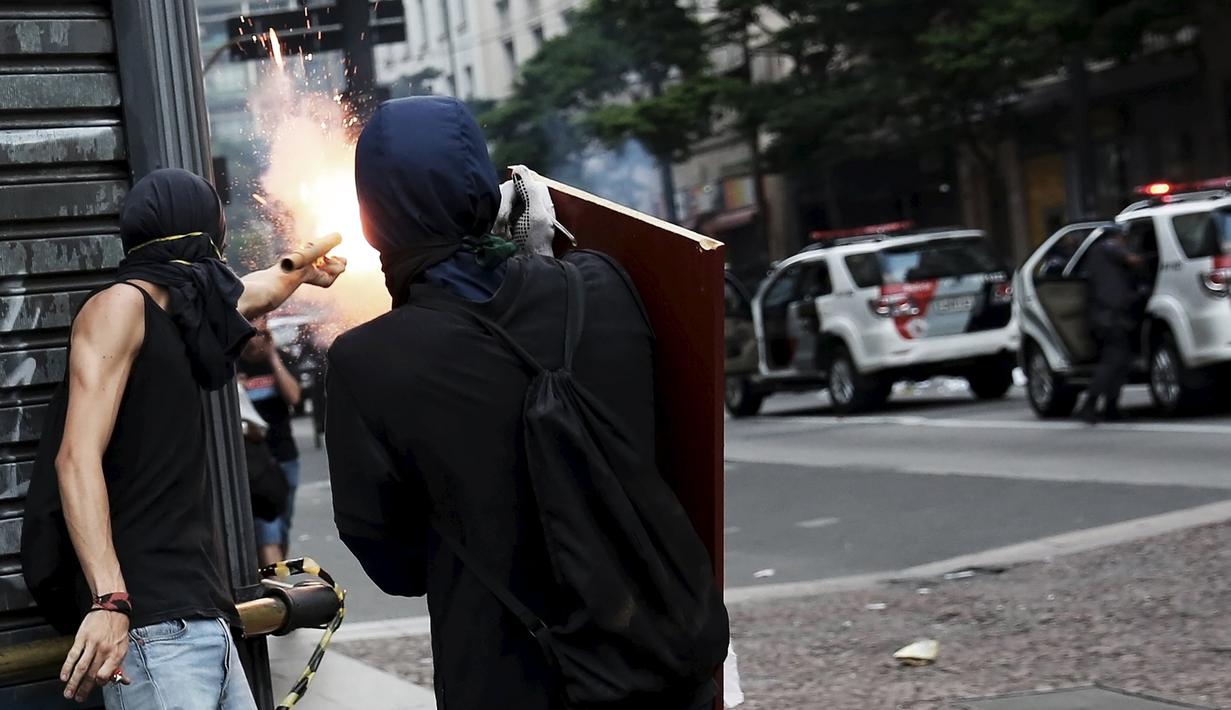 Seorang demonstran menembakkan bom rakitan saat aksi unjuk rasa di Brasil, Jumat (8/1/2016). Aksi tersebut sebagai bentuk protes terhadap kenaikan tarif untuk bus kota di Sao Paulo. (Reuters/Nacho Doce)