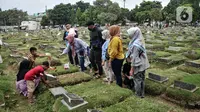 Sekelompok warga menaburkan bunga ke atas salah satu makam kerabat di TPU Kemiri. (merdeka.com/Iqbal S. Nugroho)