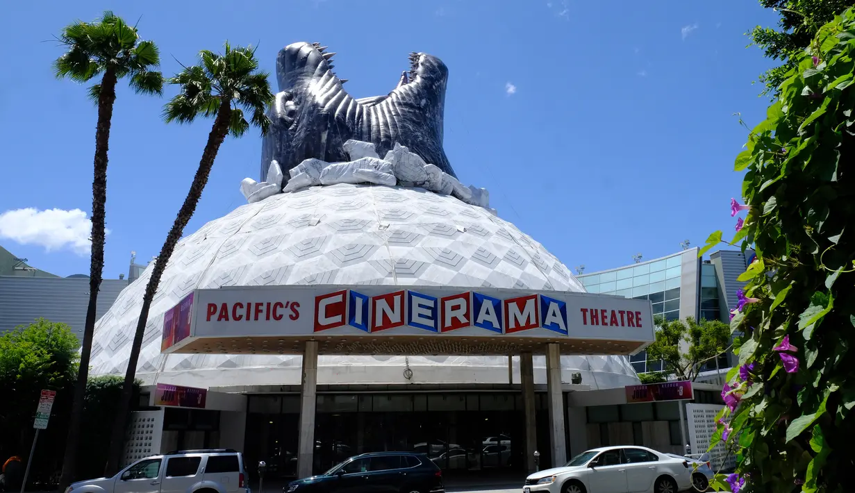 Sejumlah kendaraan terparkir depan bioskop Cinerama Dome yang atapnya dihiasi godzilla raksasa di Hollywood, California, AS pada 20 Mei 2019. Hinggapnya godzilla raksasa untuk menyambut sekuel Godzilla: King of the Monsters yang akan dirilis pada 31 Mei 2019. (Photo by Chris Delmas / AFP)