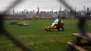 Seorang pekerja yang mengenakan alat pelindung diri memotong rumput di Bushwick Inlet Park, Wilayah Brooklyn, New York, AS (12/11/2020). AS melaporkan 143.408 kasus baru COVID-19 pada Rabu (11/11), rekor peningkatan harian sejak merebaknya pandemi di negara itu. (Xinhua/Michael Nagle)