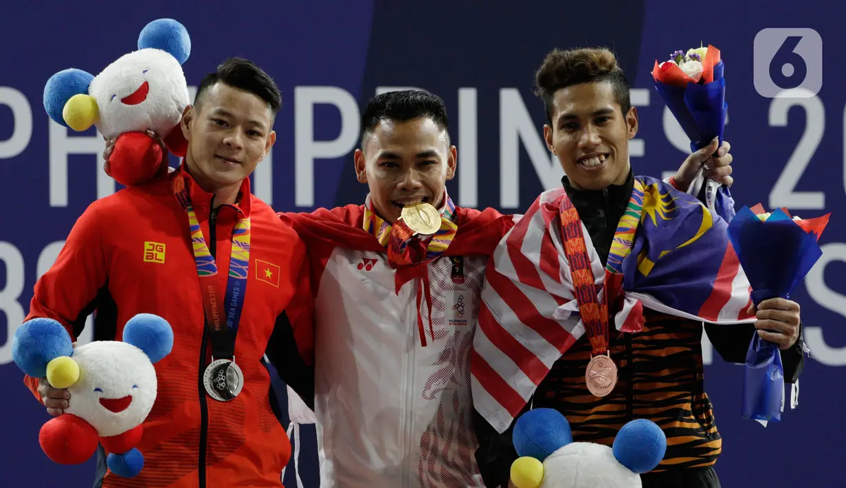 Lifter Eko Yuli (tengah) melakukan selebrasi saat mendapatkan medali emas SEA Games 2019 cabang angkat besi nomor 61 kg di Stadion Rizal Memorial, Manila, Filipina, Minggu (1/12/2019). Dirinya meraih emas dengan total angkatan 309 kg. (Bola.com/M Iqbal Ichsan)