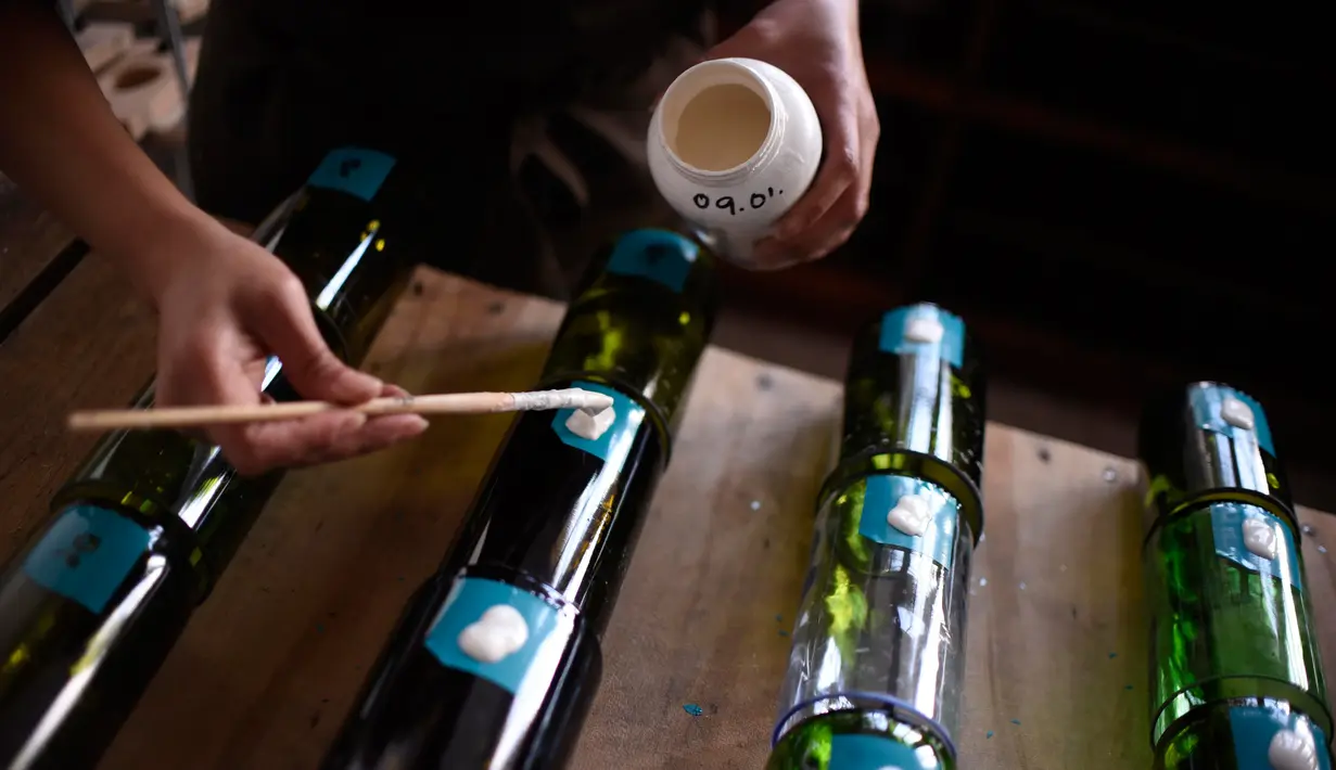 Pengrajin melakukan proses pengecatan pada gelas, Guatemala (12/2). Warga Guatemala memanfaatkan limbah botol bekas menjadi gelas cantik yang bernilai tinggi. (AFP PHOTO/JOHAN Ordonez)