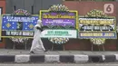 Pejalan kaki melintas dekat karangan bunga duka cita atas meninggalnya Ratu Elizabeth II di depan Kedutaan Besar (Kedubes) Inggris, kawasan Kuningan, Jakarta, Jumat (9/9/2022). Ratu Elizabeth II memerintah Inggris Raya dan 14 wilayah Persemakmuran lainnya, dan menjadi salah satu wanita paling terkenal dalam sejarah. (Liputan6.com/Herman Zakharia)