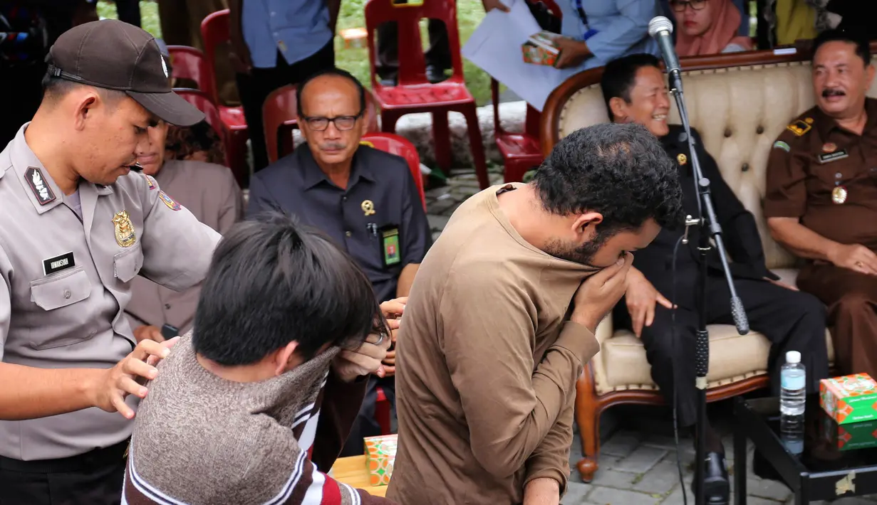 Petugas mengawal dua terpidana kasus liwath alias gay di sebuah masjid di Banda Aceh, Indonesia (23/5). Dua orang pria tersebut menerima hukuman cambuk sebanyak 85 kali karena melakukan hubungan seks homoseksual. (AP Photo / Heri Juanda, File)