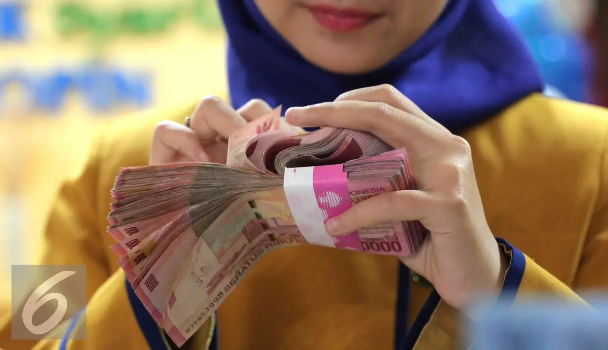 Petugas Bank menghitung uang pecahan Rp100.000 di Bank Bukopin Syariah, Jakarta, Selasa (29/12). Di pasar spot, Senin (28/12), rupiah melemah tipis 0,08% ke Rp 13.642 per dollar AS. (Liputan6.com/Angga Yuniar)