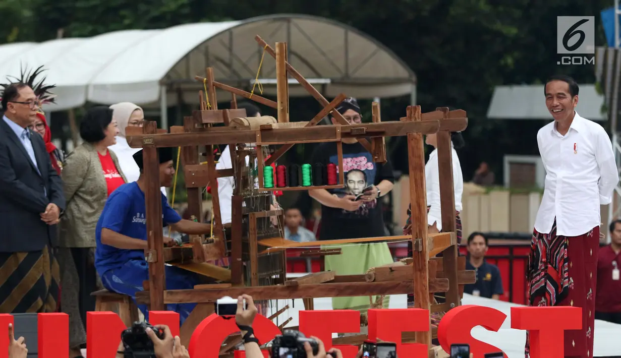 Presiden Joko Widodo melihat proses penenunan kain di Festival Sarung Indonesia 2019, Plaza Tenggara Kompleks GBK, Jakarta, Minggu (3/3). Festival ini untuk menghidupkan kesadaran generasi muda akan kekayaan budaya. (Liputan6.com/Helmi Fithriansyah)