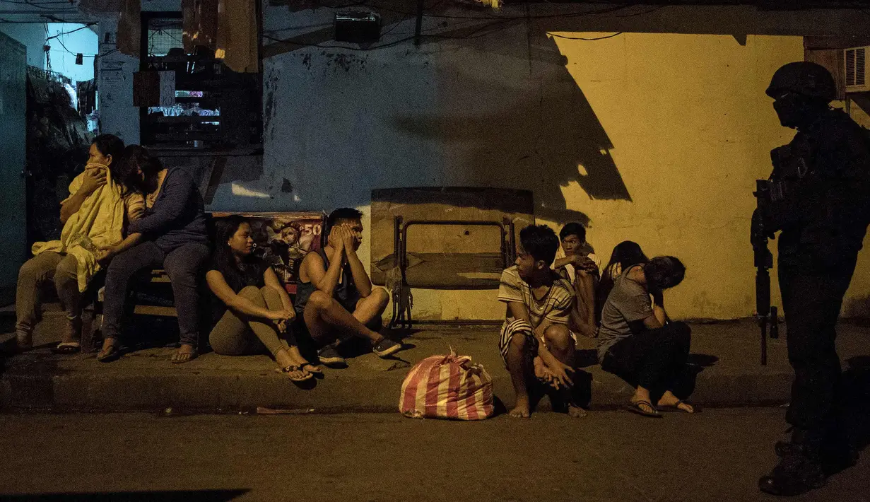 Seorang agen Drug Enforcement Agency (PDEA) Filipina mengamankan penduduk setempat selama serangan penggerebekan bandar narkoba di Desa Maharlika, Taguig, selatan Manila (28/2). (AFP Photo/Noel Celis)
