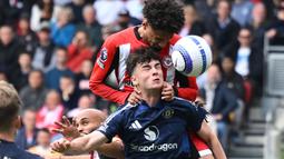 Pemain Manchester United, Tyler Fredricson (bawah) berduel udara dengan pemain Brentford, Kevin Schade dalam laga lanjutan Liga Inggris 2024/2025 di Gtech Community Stadium, London, Inggris, Minggu (04/05/2025) waktu setempat. (AFP/Justin Tallis)