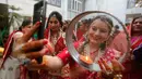Seorang wanita Hindu memandangi foto suaminya di ponsel ketika melakukan ritual festival Karva Chauth di Ahmadabad,  Kamis (17/10/2019). Selama festival, wanita-wanita yang sudah menikah di India berpuasa sepanjang hari dan memohon umur panjang serta keselamatan untuk suami mereka. (AP/Ajit Solanki)