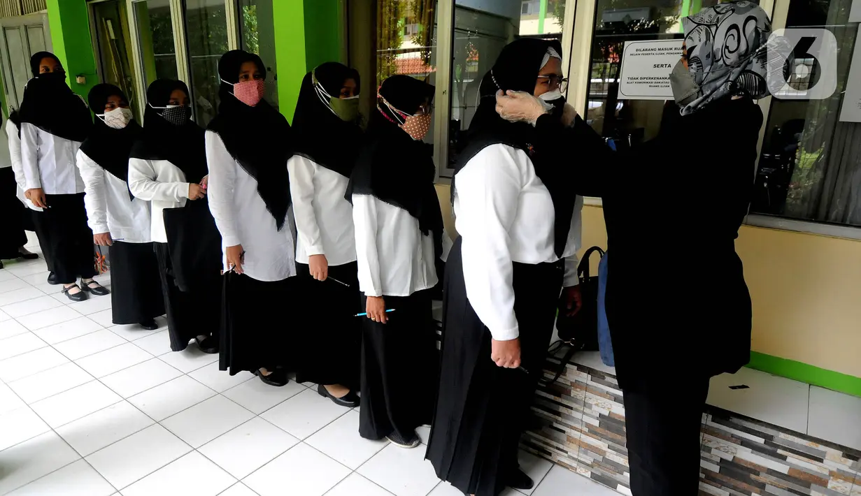 Peserta diperiksa seluruh badannya sebelum pelaksanaan ujian seleksi kompetensi P3K Guru di SMKN 2, Depok, Jawa Barat, Selasa (14/9/2021). Kemendikbud mulai Senin (13/9) secara serentak di Indonesia dilaksanakan ujian Seleksi Kompetensi P3K yang tersebar di 1000 lokasi. (merdeka.com/Arie Basuki)