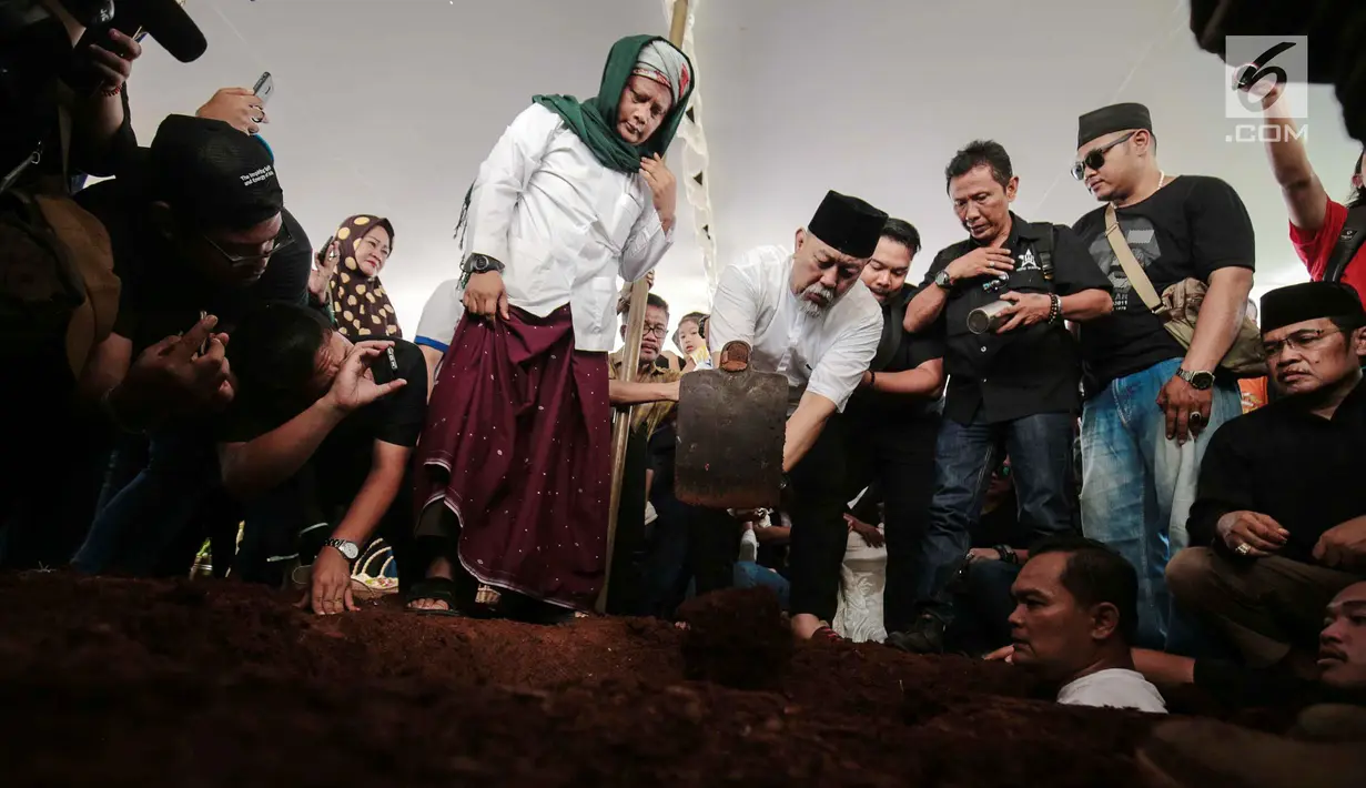 Komedian Indro Warkop menggali makam untuk mendiang istrinya, Nita Octobijanthy di TPU Tanah Kusir, Jakarta, Rabu (10/10). Nita meninggal di usia 59 tahun. (Liputan6.com/Faizal Fanani)