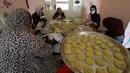 Para perempuan Palestina dengan masker dan sarung tangan menyiapkan biskuit tradisional menjelang Idul Fitri di sebuah rumah di kota tua Hebron, Tepi Barat yang diduduki, Selasa (19/5/2020). Biskuit-biskuit itu akan dijual secara online guna menjaga jarak selama pandemi Covid-19. (HAZEM BADER/AFP)