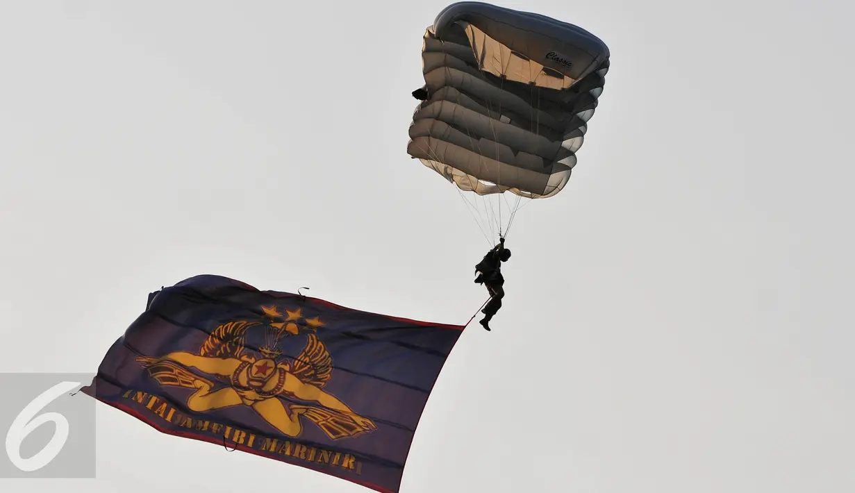 Atraksi terjun payung dengan membawa bendera saat peresmian markas baru Batalyon Intai Amfibi - 2 Korps Marinir, Jakarta, Jum'at (26/6/2015). Beragam atraksi militer diperagakan dalam acara tersebut. (Liputan6.com/Andrian M Tunay)