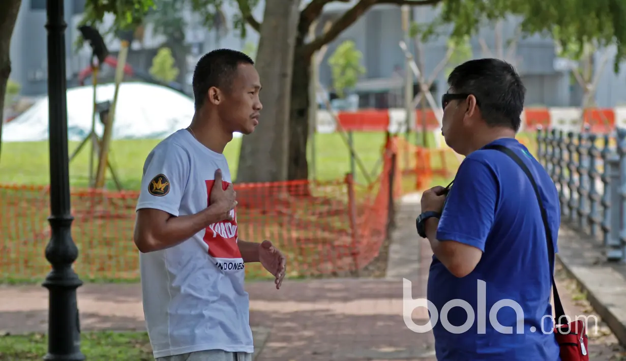 Daud Yordan berkonsultasi dengan asisten pelatih pada sesi latihan ringan di Areal Pedestrian, Singapura, Jumat (24/3/2017).  Daud Yordan akan melawan  petinju Thailand Campee Phayom Sabtu (25/3/2017). (Bola.com/Nicklas Hanoatubun)