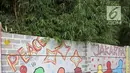 Seorang anak kecil berjalan di sisi tembok yang terdapat lukisan mural di kawasan Kramat Jati, Jakarta, Rabu (4/4). Mural yang ada di tempat ini mencerminkan pesan-pesan sosial positif kepada masyarakat. (Liputan6.com/Herman Zakharia)