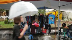 Beberapa pengunjung melintas di antara deretan stand produk pada Festival Kemang yang berlangsung di Jalan Kemang Raya, Jakarta (7/11/2015). Hujan deras disertai angin kencang mewarnai Festival Kemang hari pertama. (Liputan6.com/Helmi Fithriansyah)
