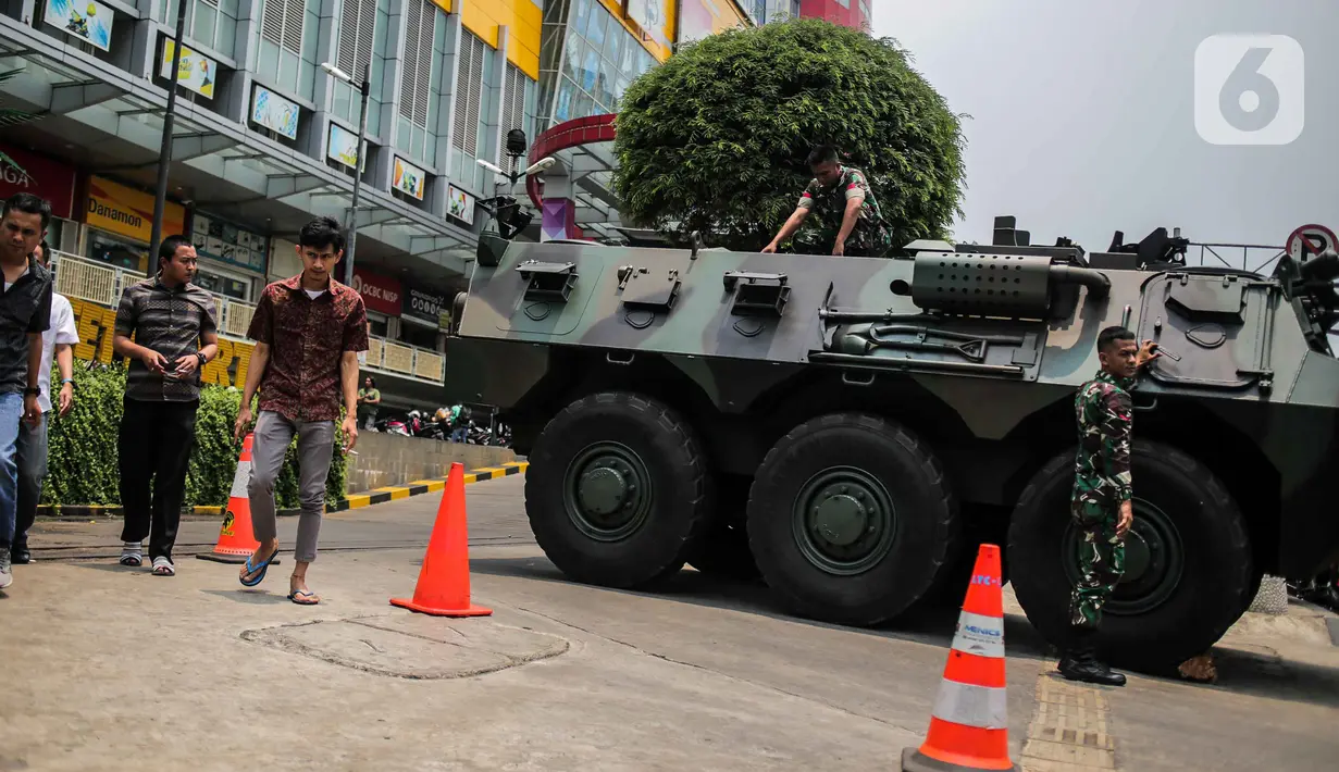 Pejalan kaki melintas dekat kendaraan taktis milik TNI, Panser Anoa yang disiagakan di kawasan LTC Glodok, Jakarta, Jumat (18/10/2019). Menjelang pelantikan Presiden dan Wakil Presiden, kawasan Glodok menjadi salah satu titik yang diperketat pengamanannya. (Liputan6.com/Faizal Fanani)