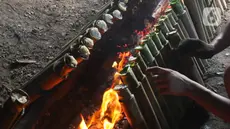 Pekerja membakar lemang di kawasan Kwitang, Jakarta, Minggu (9/3/2025). (Liputan6.com/Herman Zakharia)