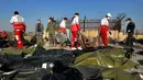 Tim penyelamat mengumpulkan jasad korban jatuhnya pesawat Boeing 737-800 di Shahedshahr, Iran, Rabu (8/1/2020). Korban tewas terdiri dari 167 penumpang dan sembilan kru pesawat. (AP Photo/Ebrahim Noroozi)