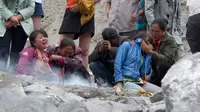 Keluarga korban menangis saat membakar dupa dan kertas ritual untuk menenangkan arwah orang yang tewas di lokasi tanah longsor di desa Xinmo, Sichuan, China (25/6). (AP Photo / Ng Han Guan)
