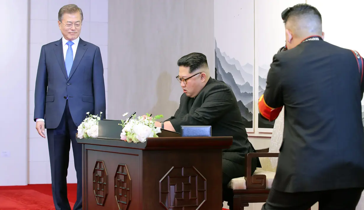 Presiden Korea Selatan, Moon Jae-in menyaksikan Pemimpin Korea Utara, Kim Jong-un menandatangani buku tamu sebelum melakukan pertemuan antar-Korea di Peace House, Jumat (2/4). Di buku tamu, Jong-un menulis kalimat perdamaian. (KOREA SUMMIT PRESS POOL/AFP)