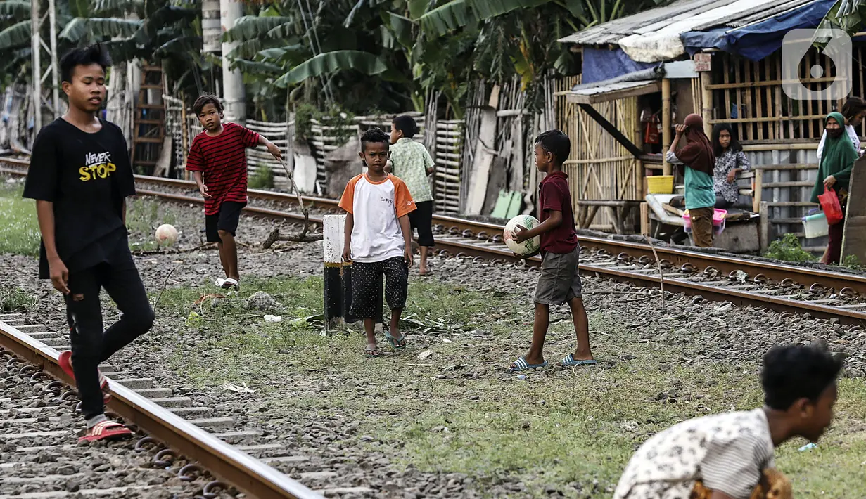 Anak-anak bermain bola di tengah perlintasan kereta api kawasan Ancol, Jakarta Utara, Kamis (19/5/2022). Kelompok umur kasus diduga hepatitis akut terbanyak adalah di bawah 5 tahun ada tujuh kasus, 6 sampai 10 tahun ada dua kasus, dan 11-16 tahun ada lima kasus. (Liputan6.com/Johan Tallo)