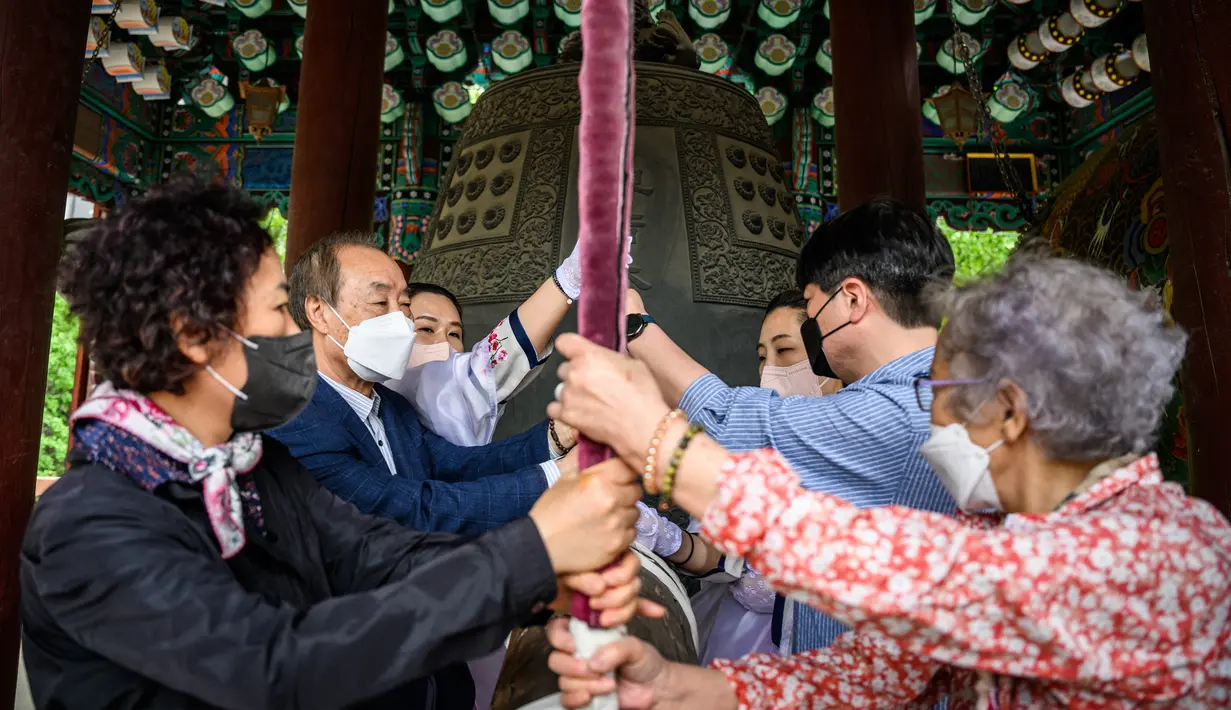 <p>Para jemaah membunyikan lonceng besar setelah kebaktian untuk merayakan ulang tahun Buddha di Kuil Jogye, Seoul, Korea Selatan, Minggu (8/5/2022). (ANTHONY WALLACE/AFP)</p>